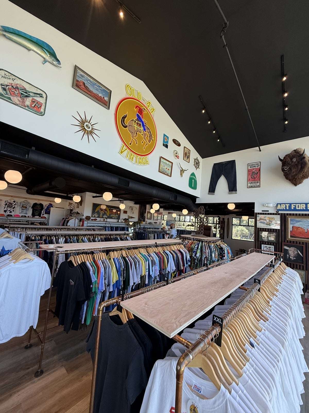 The wall of Old 44 Vintage covered in neon, fish signs, plates, and a buffalo mount